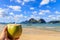 Hand holding a coconut coco loco coctail with straw, tropical islands, beach, sea and blue sky in the background, El Nido, Palawan