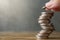 Hand holding a coin to put on Stack of coins  on wood desks and loft wall backgrounds with sunlight