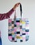 Hand holding colorful quilted patchwork tote bag