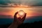 Hand Holding Crystal Ball Against Vivid Sunset Sky