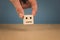 Hand holding a cube with a neutral smiley on a blue background