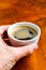 Hand holding cup of coffee in a nice hipster cafe. Soft focused image.