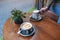 a hand holding a cup of hot chocolate with another cup of coffee on wooden table