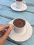 Hand holding a cup of Turkish Greek coffee on wooden table