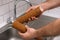 Hand holding dirty water filter cartridge over the sink. Brown coloring. Evidence of contamination of tap water with