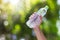 Hand holding drinking water bottle on blurred green bokeh background