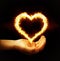 Hand holding fire heart on black background