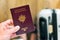 Hand holding a french - european passport with luggage in the ba