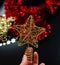 Hand holding a glittery star Christmas topper. Christmas concept
