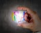 Hand holding glowing colorful transparent glass cubic