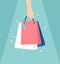 Hand holding glowing shopping bags unger light on a green background. Vector illustration