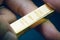 Hand holding gold bar as investment asset or safe haven on financial crisis, shinny ingot or bullion studio shot with dark