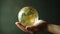 Hand holding a green earth globe, in the style of light amber, organic modernism, sharp focus while maintaining a pleasing