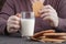 Hand holding half bite cookie with milk