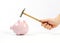 Hand holding hammer and upside down pink piggy bank