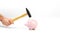 A hand holding a hammer which is raised above a standing pink piggy bank