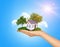 Hand holding house on green grass with tree, solar