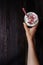 Hand holding Ice coffee drink on the wooden table, with copy space. Top view