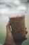 Hand holding iced mocha with straw in plastic cup