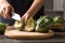 Hand holding kitchen knife and cutting green artichoke