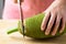 Hand holding kitchen knife and cutting young jackfruit