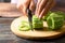 Hand holding knife and cutting bitter melon or bitter gourd