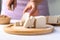 Hand holding knife and cutting organic tofu on wooden board