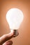 Hand holding light bulb on the beige background