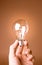 Hand holding light bulb on the beige background