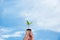 Hand holding on light bulb with green plant inside for saving earth, nature blue sky background.