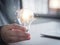 Hand-holding the light bulb represents creativity, invention, and brainstorming professional solutions to corporate success.