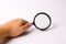 A hand is holding a magnifying glass against a white background. Find information and things, special search capabilities.