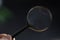 hand holding magnifying glass in dark room. concept of uncovering mystery, detective investigation, solve secret