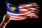 hand holding malaysia flag isolated on black background with clipping path, Hand waving Malaysia flag also known as Jalur Gemilang