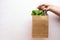 Hand holding mix of fresh salad in eco package on a rose wooden background.Food delivery.Healthy eating