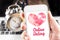 Hand holding mobile with red heart and online dating word on screen with clock and laptop at background, Internet love concept