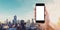 Hand holding mobile smart phone blank white screen, panoramic Bangkok city in sunrise