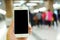 Hand holding mockup smartphone with subway passengers background