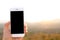 Hand holding mockup smartphone with sunlight and mountain background