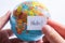 Hand holding notepaper with HELLO wording on globe