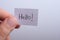 Hand holding notepaper with HELLO wording on white