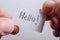 Hand holding notepaper with HELLO wording on white