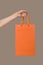 A hand is holding an orange packet. on gray background Selling