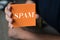 Hand holding orange paper with the word Spam, Technology Concept