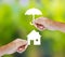 Hand holding a paper home and umbrella on green background
