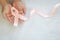 Hand holding Peach color ribbon curl on white fabric background with copy space, symbol for Uterine and Endometrial cancer