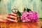 Hand holding a perfume and hydrangea wooden background