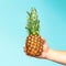 Hand holding a pineapple. Creative layout made of pineapple