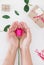 Hand holding pink rose flower with gift boxes, on white table, preparing for valentines day gift