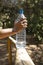 Hand holding a plastic bottle with water in the forest